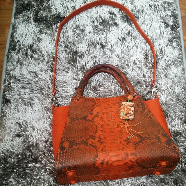Genuine Python Leather Bag (Category: Cross-body Bags) located in Singapore. Submitted by gitatan (Listing ID 90317946, Image 2). Description: Size: HxWxL(cm) 25×15×35. Orange color Condition 9.5/10. Good Quality hand made pyhthon bag. With a sling strap (L 100 cm) .