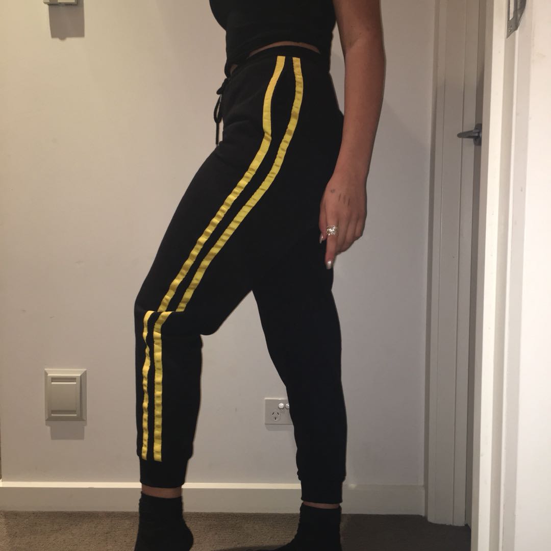 black track pants with yellow stripe