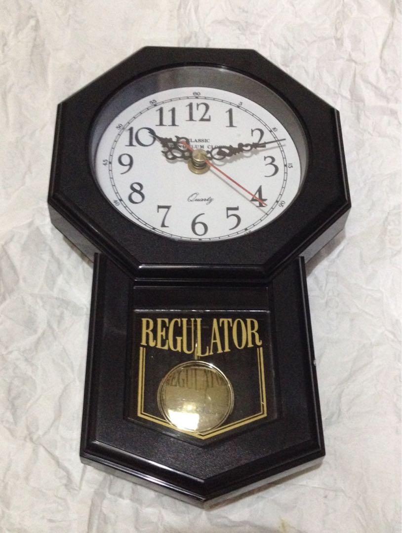Classic Wall Clock With Pendulum (Category: Clocks) located in Makati City. Submitted by citromon_potpourri (Listing ID 188376395, Image 1). Description: Body made of thermoplastic, has a gold bezel, white face, black hands and numbers. Sweep mode second hand and pendulum movement. No Chime..