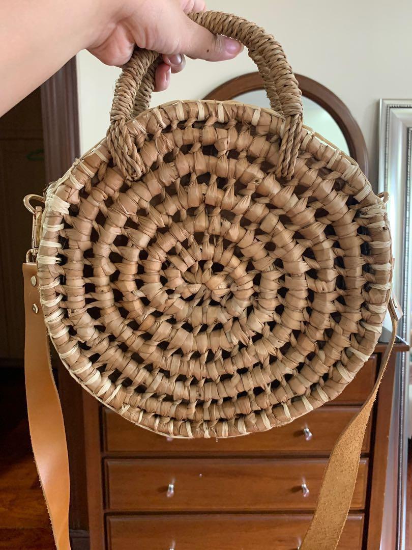 Elinora PH round rattan bag (Category: Beach Bags) located in Makati City. Submitted by _stepau (Listing ID 230748310, Image 2). Description: Round rattan bag from Elinora PH, with a detachable brown leather trap and snap closure. Bought last 2017 but never used, just stored. Bought for somewhere between Php1800-1950. RFS: Never got to use it.