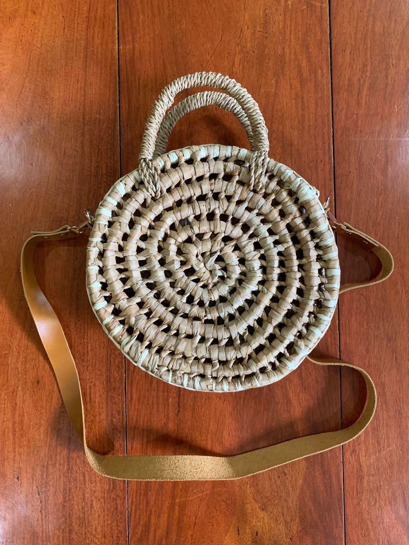 Elinora PH round rattan bag (Category: Beach Bags) located in Makati City. Submitted by _stepau (Listing ID 230748310, Image 1). Description: Round rattan bag from Elinora PH, with a detachable brown leather trap and snap closure. Bought last 2017 but never used, just stored. Bought for somewhere between Php1800-1950. RFS: Never got to use it.