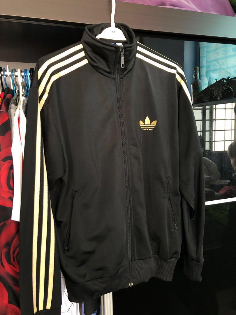 black adidas with gold stripes