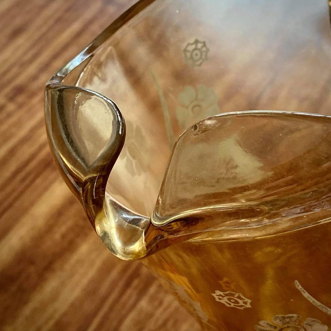 Amber Depression Glass Pitcher Vintage (Category: Pitchers & Dispensers) located in Quezon City. Submitted by tinymommy_ (Listing ID 1038006899, Image 2). Description: Amber Depression Glass Pitcher •Type: Tall handled pitcher with spout. •Color: Amber (golden-brown). •Design: Stylized floral etching, with blossoms and long sweeping leaves. •Era: Likely 1930s–1940s, a popular time for etched amber pitchers. Item Defect: Small chip sa loob ng mout