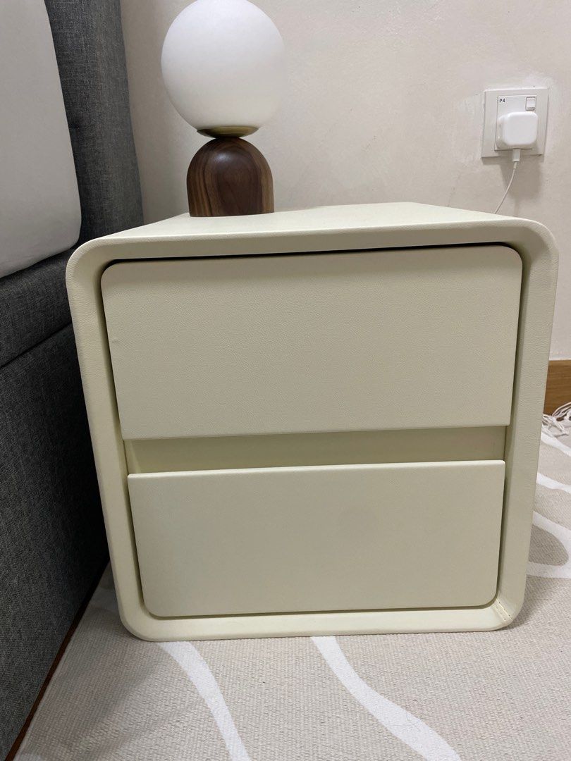 Bedside table (Category: Shelves, Cabinets & Racks) located in Singapore. Submitted by blessedtulip (Listing ID 1197723916, Image 2). Description: Brand new, just arrived. Faux leather off white colour. 35cm x 40cm x 50cm Arrange self pick up. 2 drawers with soft closing. Need to drill the 4 wooden legs (have yet to do it, still in bag brand new).