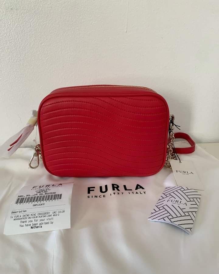 Furla Swing Mini Crossbody Red (Category: Cross-body Bags) located in San Pedro. Submitted by anne.studio (Listing ID 1203359224, Image 1). Description: Furla Swing Mini Crossbody Swing crossbody bag from Furla in leather featuring a top zip closure, detachable and adjustable crossbody strap, a gold toned hardware, signature logo plaque on the side and 1 main interior compartment with a zip and slip pocket. Dimensions: W 20 cm x H 14 cm x D 7 cm.
