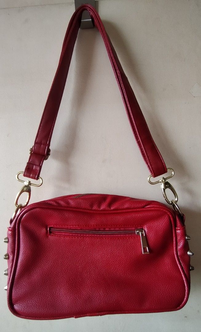 Red Leatherette Cross-body Sling Bag with Studs (Category: Cross-body Bags) located in Tanza. Submitted by lessmess.ph (Listing ID 1200710245, Image 2). Description: Red Leatherette Cross-body Sling Bag with Studs • Preloved and in good condition • With detachable and adjustable strap (buckles were replaced) • Has studded detail on sides and 1 exterior pocket with zipper • Has 2 pockets on the inside - one with zipper and one without • Approx. 24