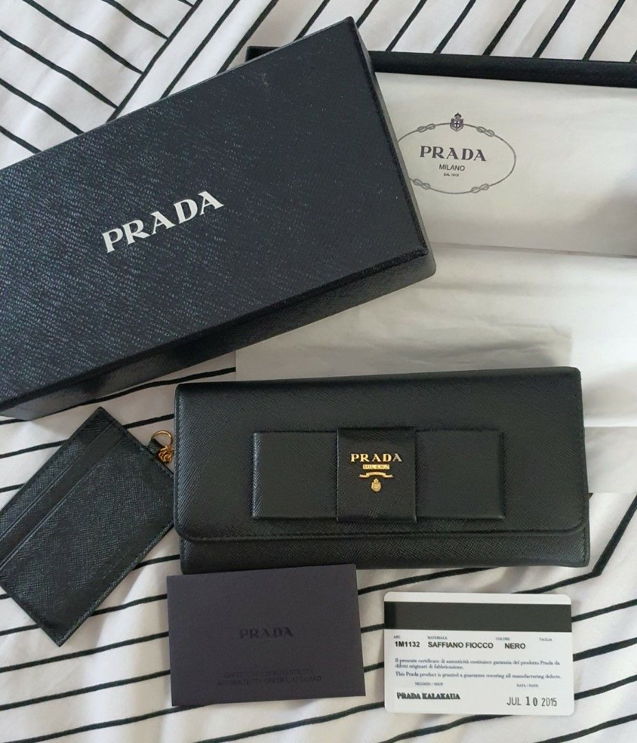 Authentic PRADA Saffiano Wallet (Category: Luxury Bags & Wallets) located in Bulacan. Submitted by stardust017 (Listing ID 1259500725, Image 2). Description: Selling my authentic Prada Saffiano Bow Wallet with detachable chain card slot Flaws: Minimal Corner rubs on the right side of the wallet (not noticeable since the wallet is black) and loose stitching on the interior zip handle. Due to age, some hardware are a bit faded but can easily be res