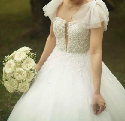 Pre-loved Wedding Gown (Category: Evening dresses & gowns) located in Paranaque City. Submitted by stefniechua (Listing ID 1260804451, Image 1). Description: Pre-loved Wedding Gown Worn only last March 18, 2023 ✨ A-line type ✨ Detachable bow sleeves ✨ 2-way gown ✨ Fits small to medium ✨ Long trail ✨ Embellished with Swarovski crystals ✨ Soft tulle material ✨ Minimalist design Includes: ✨ 1st veil ✨ 2nd veil ✨ Cord ✨ Arrhae box ✨ Garter lace ✨ 2 P