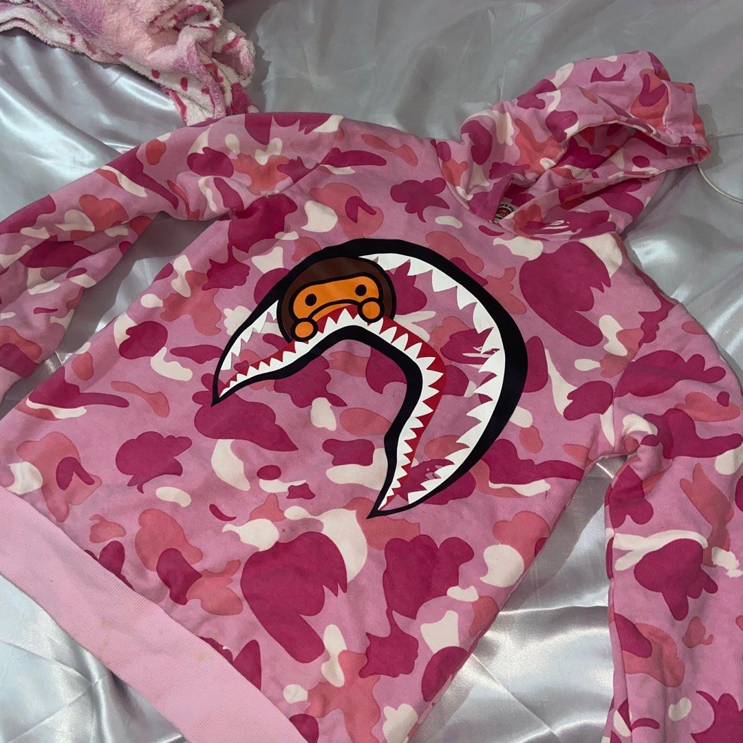 BAPE Pink Camou Hoodie (Category: Coats, Jackets and Outerwear) located in Cavite. Submitted by ginalinettilover1 (Listing ID 1261477218, Image 2). Description: rfs: need funds :) AUTH 💯!!! it’s a kid’s size (160) but it fits small body frames. swipe for ww photos :) 10/10 CONDITION!!! NO FLAWS AT ALL. this hoodie is double lined so it’s really comfy <33.