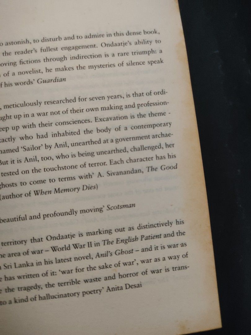 A book titled Anil's Ghost by Michael Ondaatje, displayed among other used books, highlighting its role as a literary artifact amidst everyday objects.