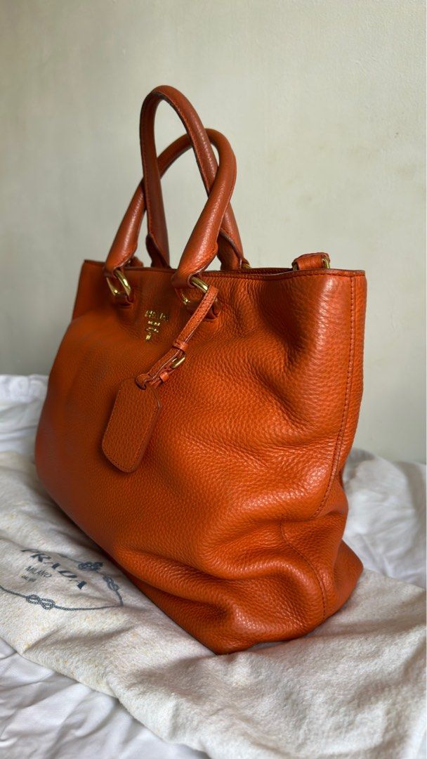 Prada Vitello Daino Papaya (Category: Luxury Bags & Wallets) located in Paranaque City. Submitted by mr.bbr (Listing ID 1267083492, Image 2). Description: Prada Vitello Daino Papaya Retail Price: $1,700 The Prada Vitello Daino Leather Tote Bag is one sophisticated piece. This durable and spacious tote has the capability to hold all your daily essentials and more. It is made of gorgeous rich pebbled Daino leather with a roomy interior and a remova