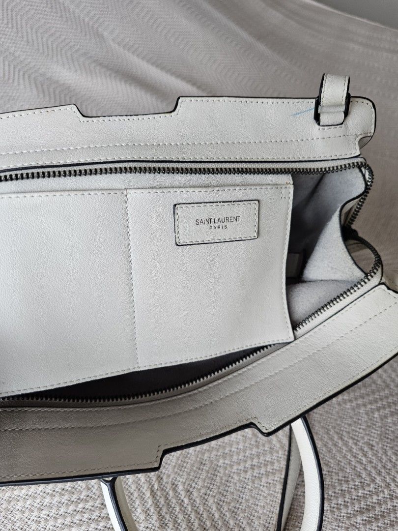 YSL Downtown Cabas Handbag white (Category: Luxury Bags & Wallets) located in Mandaluyong City. Submitted by elizadoolittl (Listing ID 1267085044, Image 2). Description: YSL Downtown Cabas handbag in white soft leather. Used only a few times. There are some small and hardly noticeable dirt on the outer leather (shown in photos), a speck of stain on the corner of the front handle, and a small streak of light blue pen ink near the zipper. Other tha