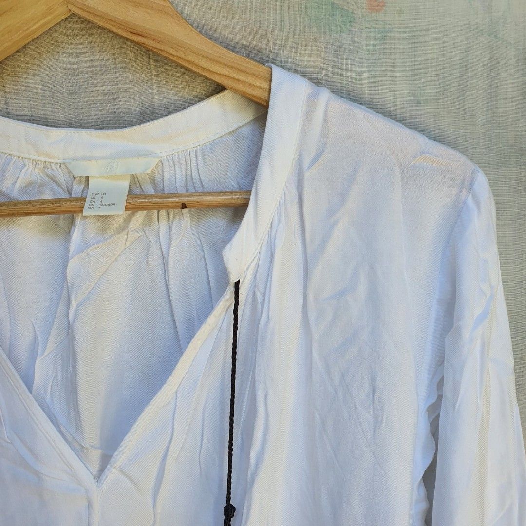 H&M classic white long sleeves blouse (Category: Longsleeves) located in Batangas. Submitted by ghostquire (Listing ID 1264127452, Image 2). Description: features a classic white viscose fabric with black tassel detailing. with extra button. presko fit! best fits s-m for your reference: width (pit to pit) 20” length 26” *needs ironing helping tags: pinterest aesthetic vintage y2k cottagecore coquette gothic academia kawaii grunge egirl indie fair