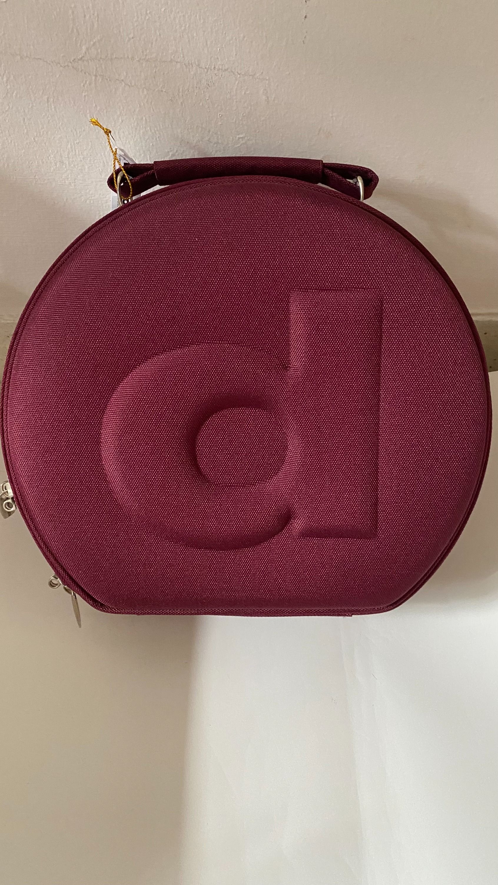 An unique and exclusive maroon red round carrying bag with zippers