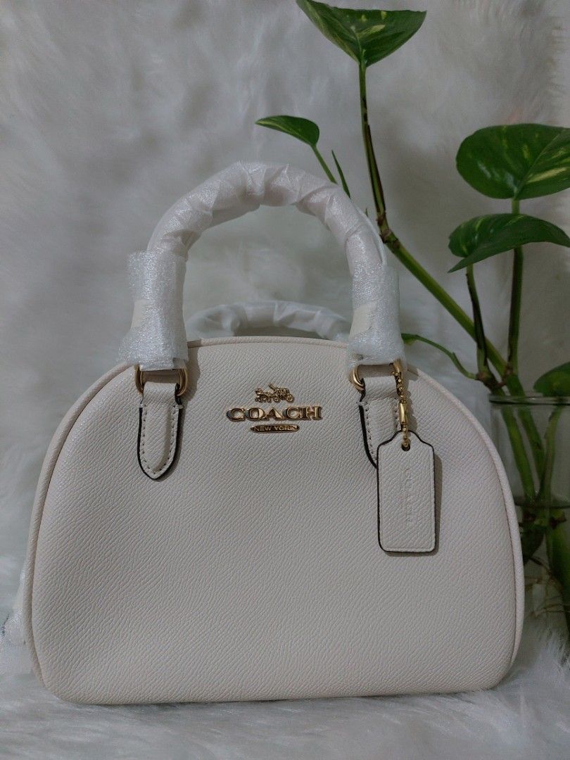 Authentic Coach Sydney Satchel (Category: Luxury Bags & Wallets) located in Quezon City. Submitted by KatieAnn (Listing ID 1217781358, Image 2). Description: 🇺🇲💯 New/Authentic/Original💯🇺🇲 Color: Gold/Chalk Material: Crossgrain Leather 👜Inside multifunction pocket 👜Zip closure, fabric lining 👜Handles with 2.75" drop 👜Detachable strap with 22.5" drop for shoulder or crossbody wear 📐Size: 8"L x 6"H x 5"W ✅️ USA-bought ✅️ Actual pictures p