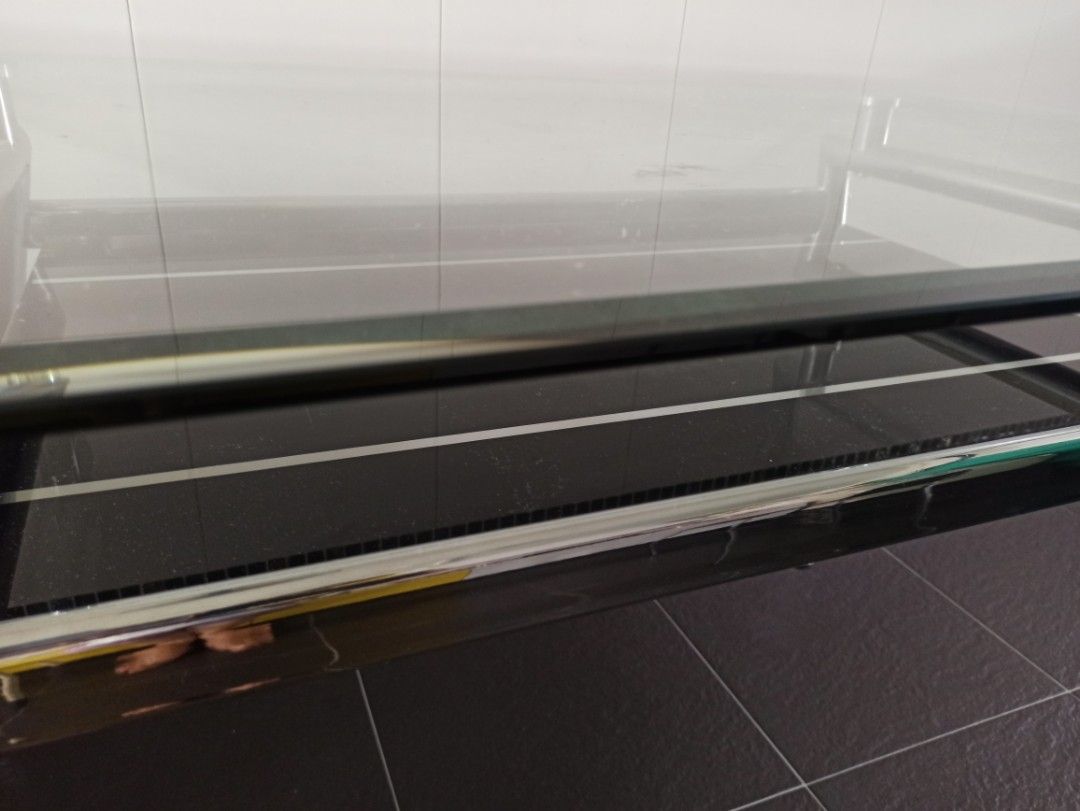 Shiny glass table with metallic stand and extra space beneath