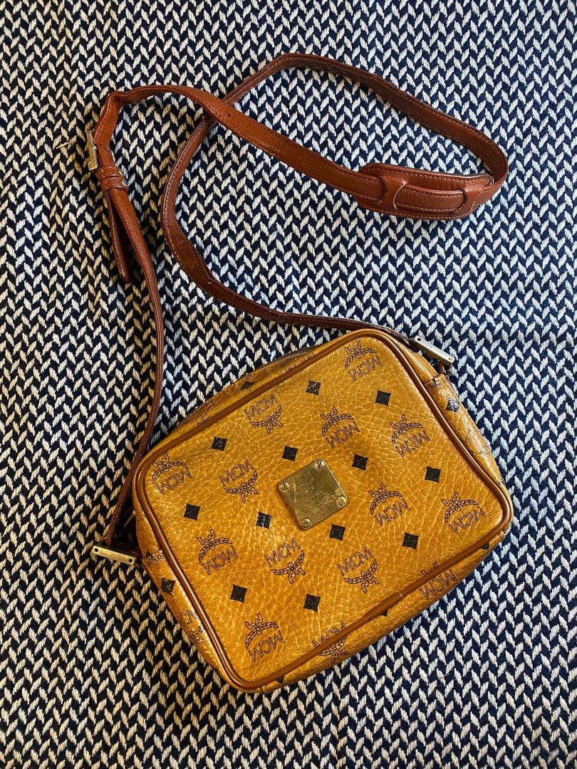 *SALE* Authentic MCM Cognac Camera Sling Bag (Category: Luxury Bags & Wallets) located in Mandaluyong City. Submitted by wear_your_style (Listing ID 1223557849, Image 1). Description: I think this is vintage kasi Munchen nalalagay. In iconic cognac color, matingkad pa. This is a slim type of camera bag measures 6 inches long, 8 inches wide, and with 2 inches depth. Sling is adjustable but not removable. Zippers are good. May zipper compartment sa