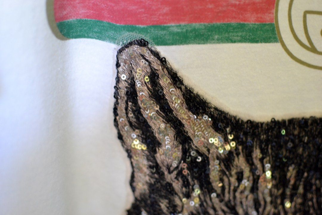 AUTHENTIC Gucci shirt (Category: Luxury Apparel) located in Akbar. Submitted by itsluxurythings (Listing ID 1230133466, Image 1). Description: 🔥ONHAND Ready to ship anytime🔥 ✅100% AUTHENTIC✅ 🩷Actual Pictures posted already 🩷 Item is in excellent condition, features is a nice Colors Green eyes Pretty Cat Sequins Patches not print., this Gucci distressed Cream color tshirt is you have like it because the cat is so so pretty in personal looks ve