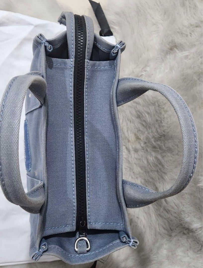 Marc Jacobs The Mini Tote Bag in Blue Shadow (Category: Luxury Bags & Wallets) located in Quezon City. Submitted by styledbyruod (Listing ID 1236994289, Image 3). Description: The Mini Tote Bag in Blue Shadow Guaranteed Authentic 10in L x 5in D x 8in H 26cm L x 13cm D x 21cm H Strap 57in L x 2in D (144cm L x 4cm D) Strap Drop 27in (69cm) Handle Drop 4in (11cm) Inclusions: Shoulder strap and dust bag With stain at the back (see pic).