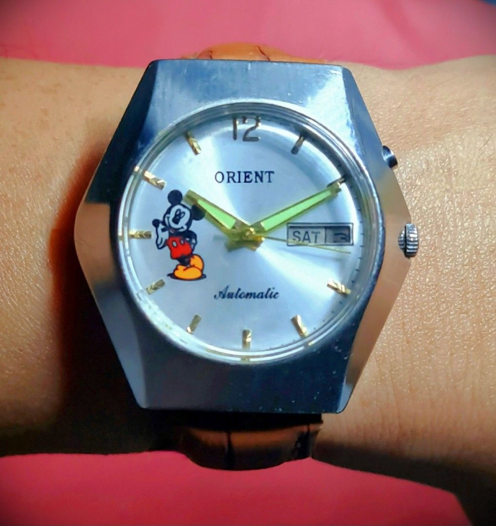 #Luxury Watch #Rare Unique #Mickey Mouse #Orient #Japan Made #Automatic (Category: Luxury Watches) located in Caloocan City. Submitted by allig8 (Listing ID 1282390680, Image 2). Description: This unique ORIENT Japanese Mickey Mouse watch boasts a stunning thick silvery case with a beautiful round shiny dial that features golden hour markers as indices. The 39mm case houses a reliable automatic movement with 21 jewels, ensuring accurate timekeepi