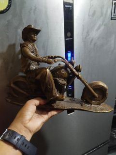 Brass cowboy riding a motorcycle statue display