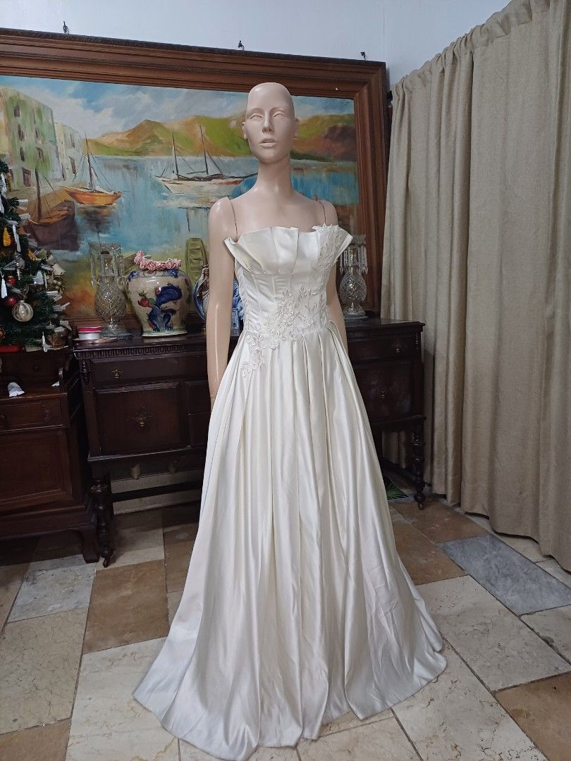Elegant Mikado Wedding Gown (Category: Evening dresses & gowns) located in Carmona. Submitted by fashionlibraryph (Listing ID 1331678385, Image 1). Description: This stunning strapless wedding gown, made from luxurious Mikado fabric, showcases a dramatic and architectural straight-across neckline. The neckline features large, expertly crafted pleats that form a striking structured look, giving the gown a bold and sophisticated edge. These pleats 