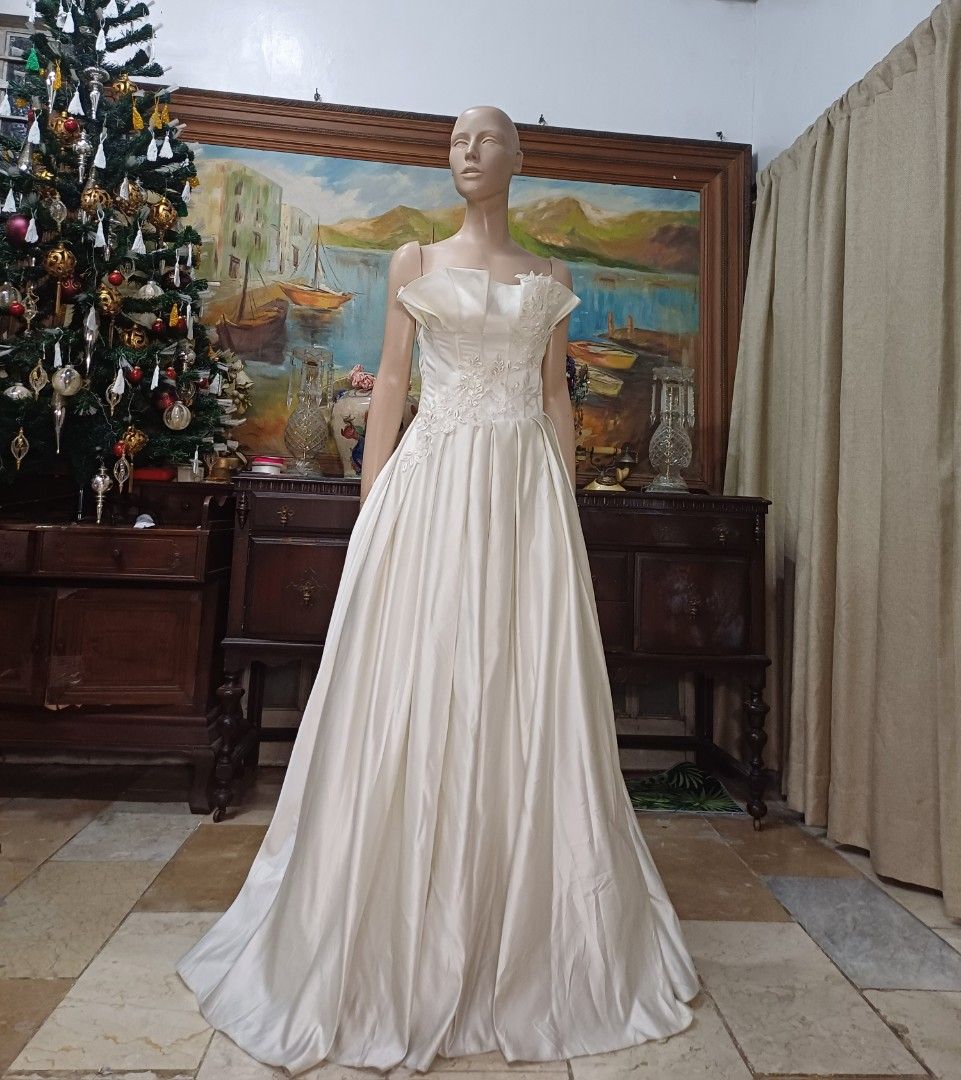 Elegant Mikado Wedding Gown (Category: Evening dresses & gowns) located in Carmona. Submitted by fashionlibraryph (Listing ID 1331678385, Image 3). Description: This stunning strapless wedding gown, made from luxurious Mikado fabric, showcases a dramatic and architectural straight-across neckline. The neckline features large, expertly crafted pleats that form a striking structured look, giving the gown a bold and sophisticated edge. These pleats 