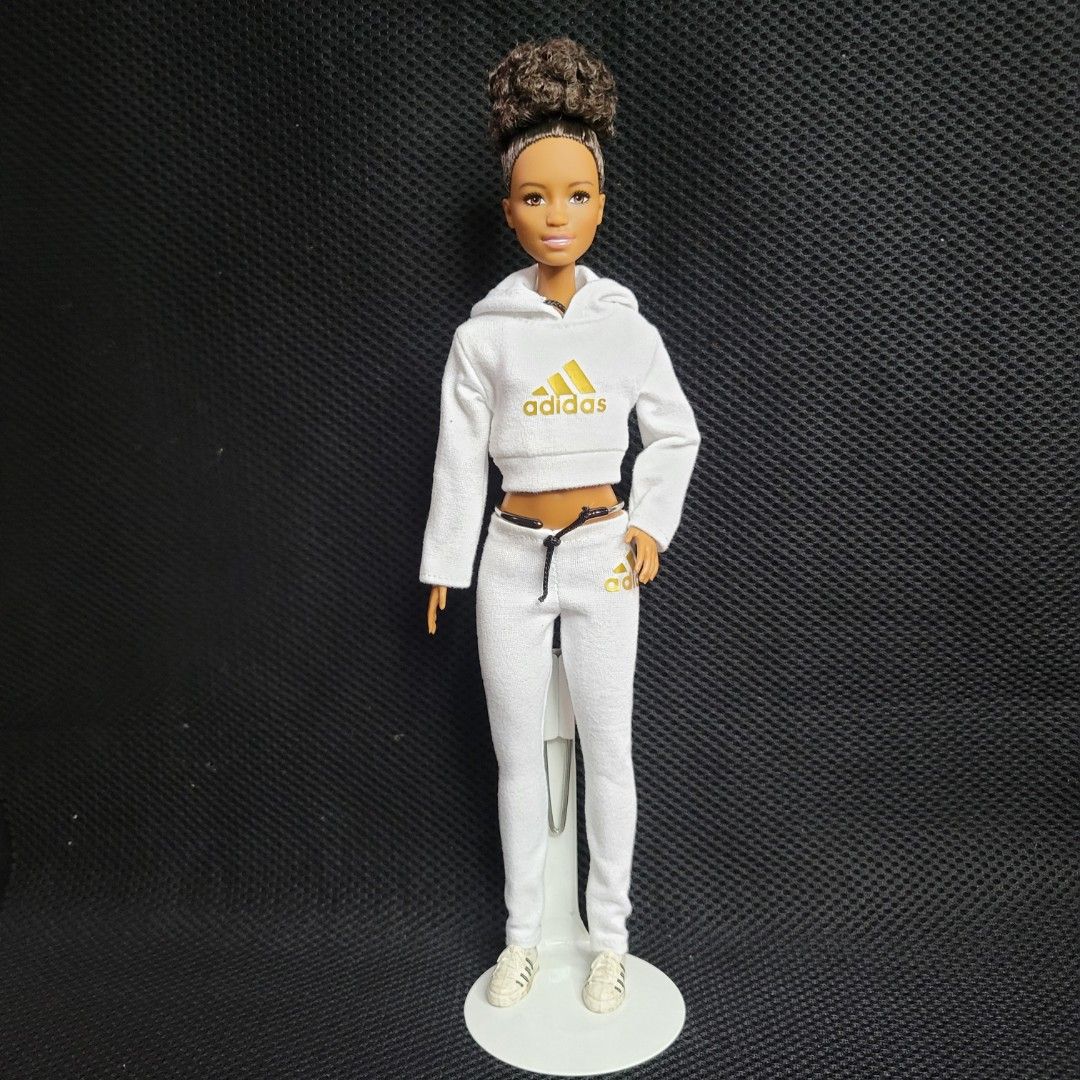 Barbie doll with curly hair (Category: Kids Toys) located in Quezon City. Submitted by aeemen (Listing ID 1336330030, Image 1). Description: Preloved, no box. Original clothes were changed to this Adidas jogger set. Doll is still in good condition. MOP: GCASH, bank transfer MOD: lalamove/grab/ J&T Buyer shoulders shipping expense. Location: Quezon City.
