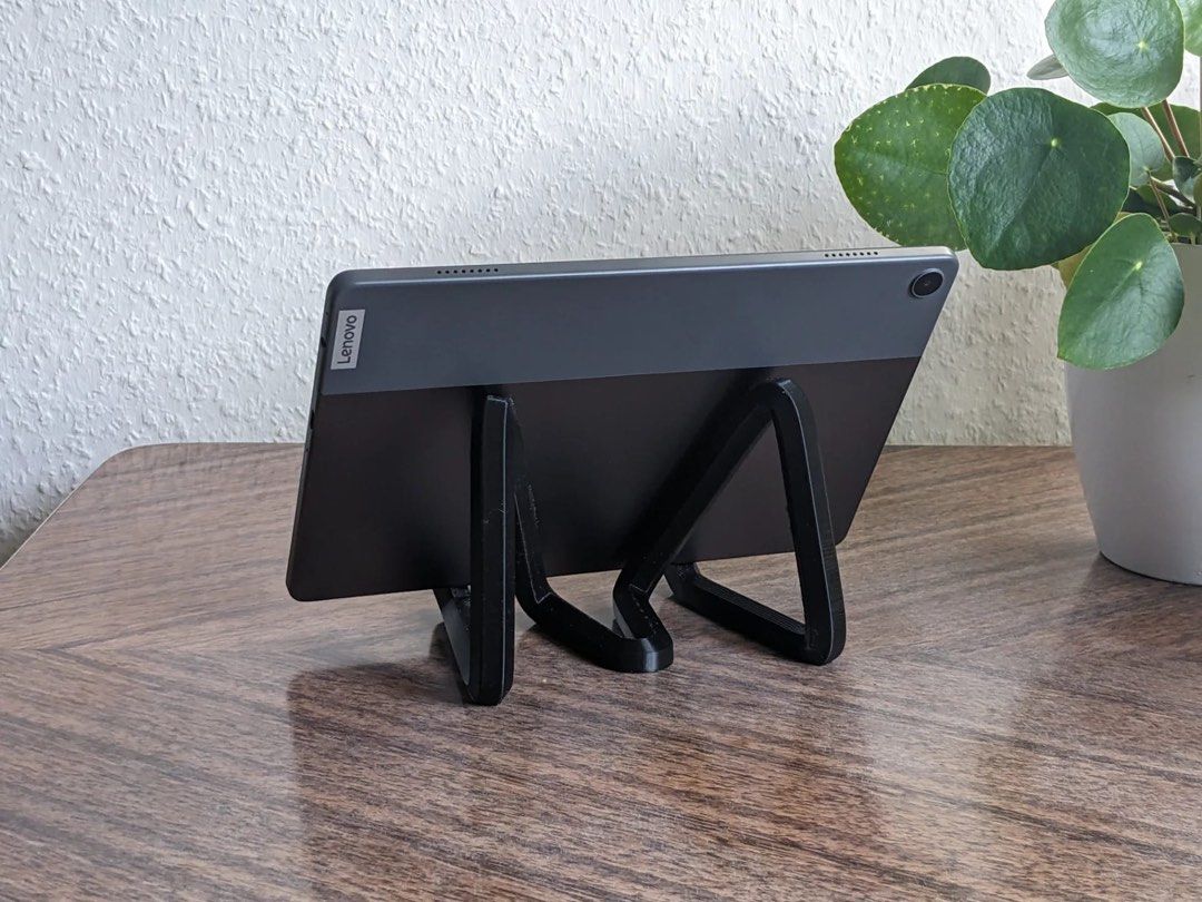 iPad stand (Category: Cables & Adaptors) located in Singapore. Submitted by cnc_engineering (Listing ID 1337560498, Image 2). Description: Elevate your iPad experience with this sleek, modern stand. Featuring a bold triangular design and a vibrant orange finish with stylish gradient accents, this stand adds a touch of sophistication to any space. Its sturdy construction and dual hooks provide a secure grip, ensuring your iPad stays in place wheth