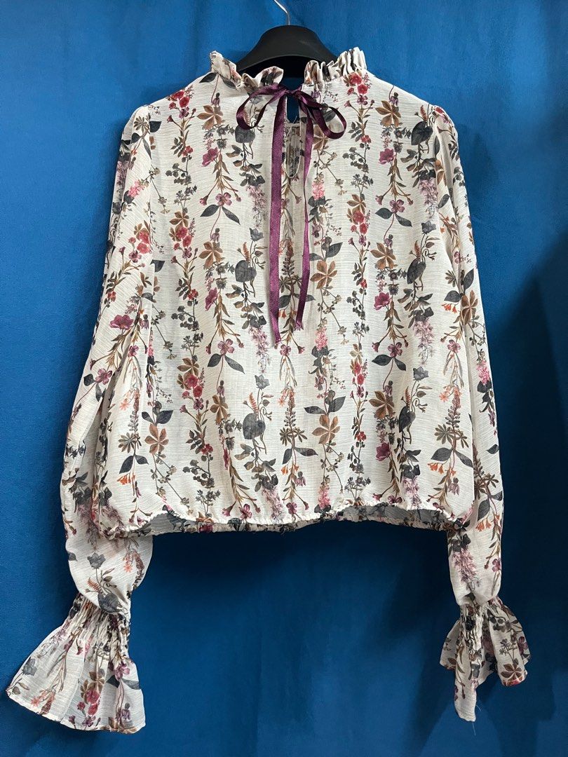 Zara Basic Cream Semi-sheer Floral Longsleeve Top (Category: Blouses) located in Quezon City. Submitted by wednesday21 (Listing ID 1335114463, Image 2). Description: Cream floral blouse with ruffled neckline and pleated design in front. Long sleeves with garterized, ruffled cuffs. Semi-cropped length in semi-sheer fabric and keyhole purple ribbon tie at the back. With delicate floral pattern in muted colors. Can fit XS-S. 3-day reservation only. 
