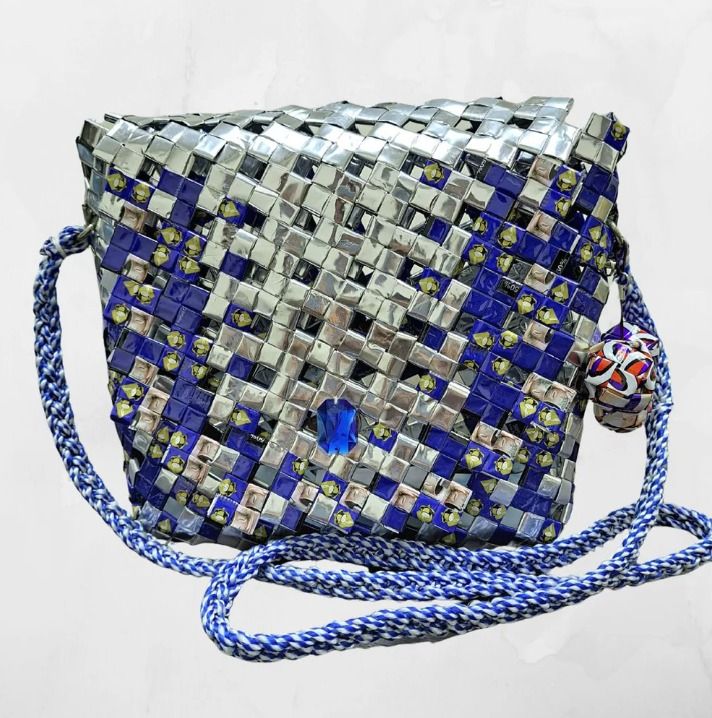 Cobalt Mist (Category: Cross-body Bags) located in Singapore. Submitted by bcaresg (Listing ID 1342409349, Image 1). Description: Handbag with sling made from recycled materials Dimensions: W: 23 cm, H: 20 cm This crossbody bag is handcrafted from recycled materials, giving a stylish new life to discarded resources. Featuring a woven design in silver and blue, with a distinctive embellishment and braided strap, this bag is both fashionable and en