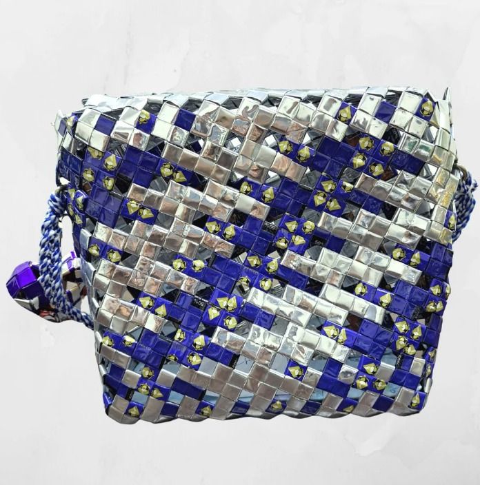 Cobalt Mist (Category: Cross-body Bags) located in Singapore. Submitted by bcaresg (Listing ID 1342409349, Image 2). Description: Handbag with sling made from recycled materials Dimensions: W: 23 cm, H: 20 cm This crossbody bag is handcrafted from recycled materials, giving a stylish new life to discarded resources. Featuring a woven design in silver and blue, with a distinctive embellishment and braided strap, this bag is both fashionable and en