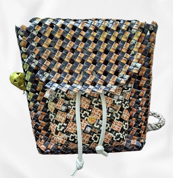 Cocoa Eclipse (Category: Backpacks) located in Singapore. Submitted by bcaresg (Listing ID 1342413809, Image 1). Description: Backpack with front pocket Dimensions: W: 28 cm, H: 28 cm This eye-catching backpack is handcrafted from recycled materials, featuring a unique woven design in black, brown, and tan. With a distinctive front pocket and drawstring closure, this bag is both stylish and sustainable. Perfect for everyday use and eco-conscious 