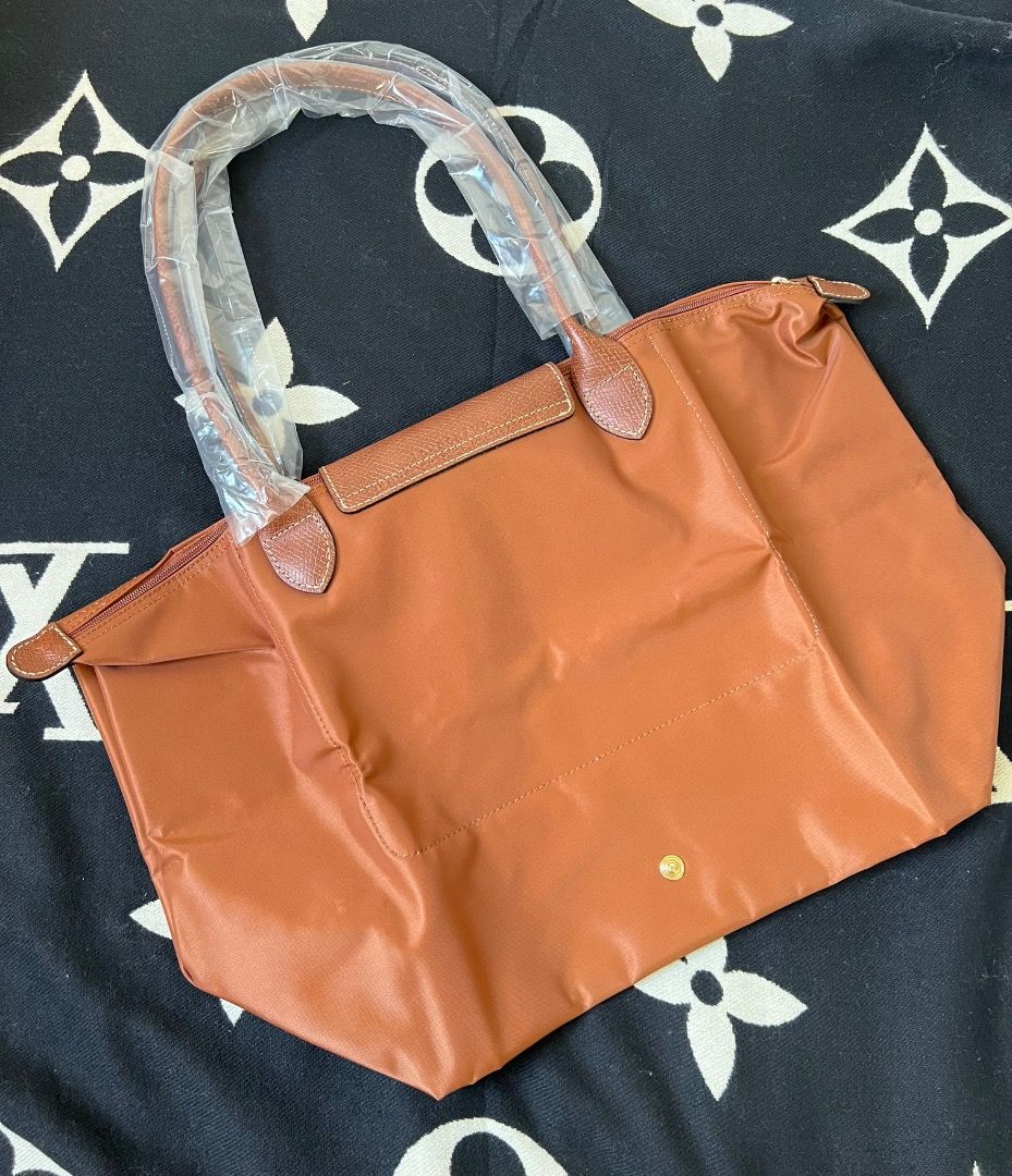 Longchamp Le Pliage Cognac Large Tote (Category: Luxury Bags & Wallets) located in Antipolo. Submitted by mjlenihcpreloved (Listing ID 1340653607, Image 2). Description: Longchamp Le Pliage Cognac Large Tote Dimensions : 31 cm (L - measured at the base of the bag) x 30 cm (H) x 19 cm (W) Material : Polyamide fabric with a minimum of 70% recycled fibers, with interior coating Metallic Hardware : gold color Closing : Zipper and snap closure.