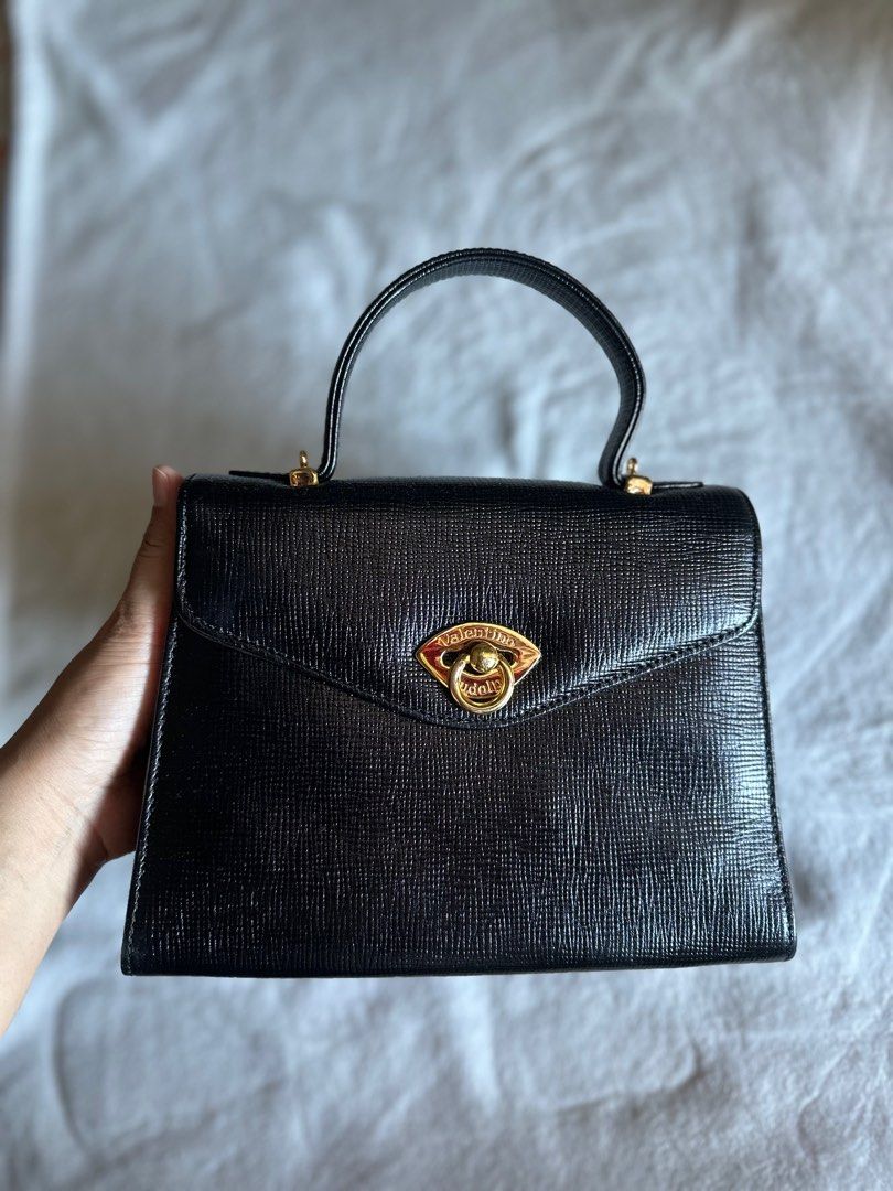 Rudolph Valentino Handbag (Category: Luxury Bags & Wallets) located in Mandaluyong City. Submitted by TheWeekendProject (Listing ID 1291883215, Image 2). Description: Rudolph Valentino stand-alone top handle handbag. Gold hardwares, no tarnish. Has sling slot (no sling) Excellent condition outside, no rubs nor scratch. Inner lining is leather, visible fading inside (see last pic) Has zipper pockets inside and outside. Classic style. Use as handba