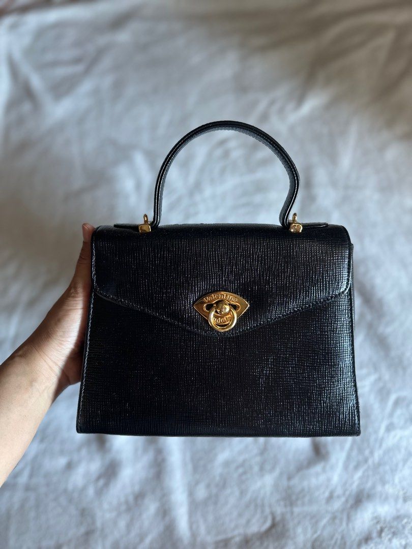 Rudolph Valentino Handbag (Category: Luxury Bags & Wallets) located in Mandaluyong City. Submitted by TheWeekendProject (Listing ID 1291883215, Image 1). Description: Rudolph Valentino stand-alone top handle handbag. Gold hardwares, no tarnish. Has sling slot (no sling) Excellent condition outside, no rubs nor scratch. Inner lining is leather, visible fading inside (see last pic) Has zipper pockets inside and outside. Classic style. Use as handba