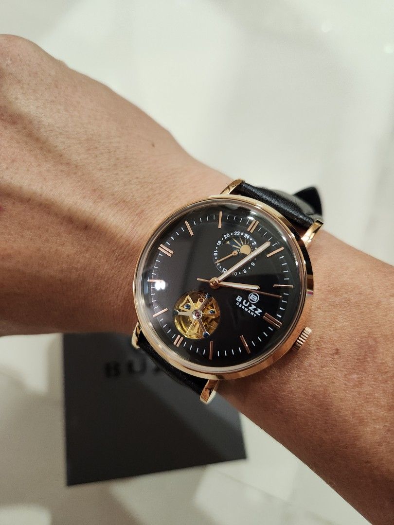 Buzz Germany Automatic Watch (Category: Men's Watches) located in Singapore. Submitted by chngck86 (Listing ID 1308638321, Image 1). Description: *Japan automatic movement *24 hours hand with Sun and Moon display *Open heart design (can see windmil rotating) *Rose gold case with black leather strap *Comes with full box.