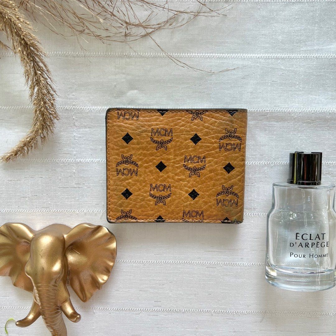 MCM Cognac Bifold Wallet (Category: Luxury Bags & Wallets) located in Floridablanca. Submitted by lj_domasian (Listing ID 1312273836, Image 2). Description: Original! MCM Cognac Bifold Wallet ₱2,800 𝗜𝗻𝗰𝗹𝘂𝘀𝗶𝗼𝗻/𝘀: None 𝑪𝒐𝒏𝒅𝒊𝒕𝒊𝒐𝒏: 8/10 - good condition ~ 𝐂𝐨𝐧𝐝𝐢𝐭𝐢𝐨𝐧 𝐝𝐞𝐬𝐜𝐫𝐢𝐩𝐭𝐢𝐨𝐧👇🏼 - minor fading on its leather on 1 corner - 2 small cracks on leather - Sign of use on its interior leather 𝗗𝗶𝗺𝗲𝗻𝘀𝗶𝗼𝗻𝘀: 👇�