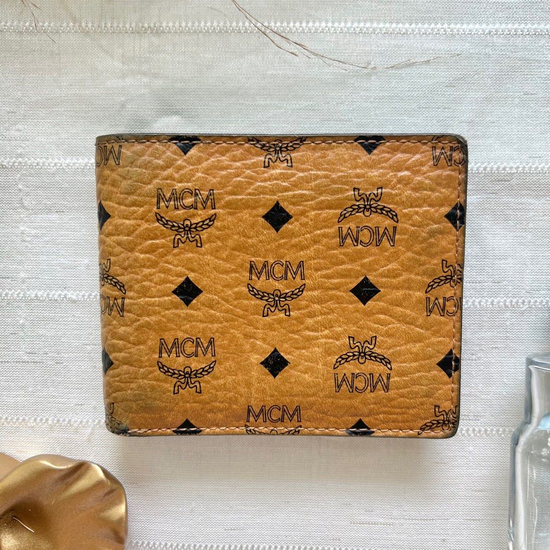 MCM Cognac Bifold Wallet (Category: Luxury Bags & Wallets) located in Floridablanca. Submitted by lj_domasian (Listing ID 1312273836, Image 3). Description: Original! MCM Cognac Bifold Wallet ₱2,800 𝗜𝗻𝗰𝗹𝘂𝘀𝗶𝗼𝗻/𝘀: None 𝑪𝒐𝒏𝒅𝒊𝒕𝒊𝒐𝒏: 8/10 - good condition ~ 𝐂𝐨𝐧𝐝𝐢𝐭𝐢𝐨𝐧 𝐝𝐞𝐬𝐜𝐫𝐢𝐩𝐭𝐢𝐨𝐧👇🏼 - minor fading on its leather on 1 corner - 2 small cracks on leather - Sign of use on its interior leather 𝗗𝗶𝗺𝗲𝗻𝘀𝗶𝗼𝗻𝘀: 👇�