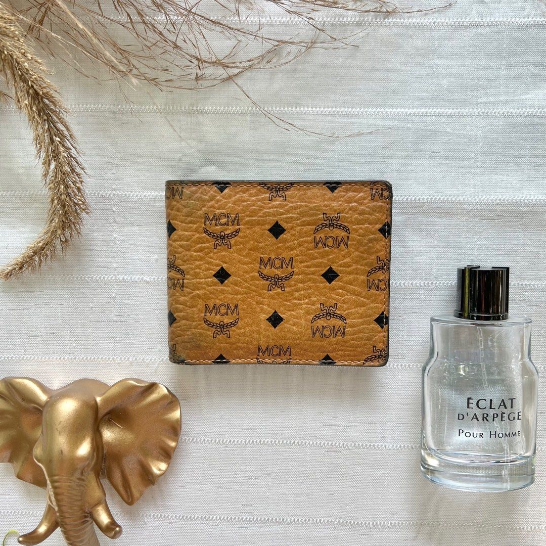 MCM Cognac Bifold Wallet (Category: Luxury Bags & Wallets) located in Floridablanca. Submitted by lj_domasian (Listing ID 1312273836, Image 1). Description: Original! MCM Cognac Bifold Wallet ₱2,800 𝗜𝗻𝗰𝗹𝘂𝘀𝗶𝗼𝗻/𝘀: None 𝑪𝒐𝒏𝒅𝒊𝒕𝒊𝒐𝒏: 8/10 - good condition ~ 𝐂𝐨𝐧𝐝𝐢𝐭𝐢𝐨𝐧 𝐝𝐞𝐬𝐜𝐫𝐢𝐩𝐭𝐢𝐨𝐧👇🏼 - minor fading on its leather on 1 corner - 2 small cracks on leather - Sign of use on its interior leather 𝗗𝗶𝗺𝗲𝗻𝘀𝗶𝗼𝗻𝘀: 👇�