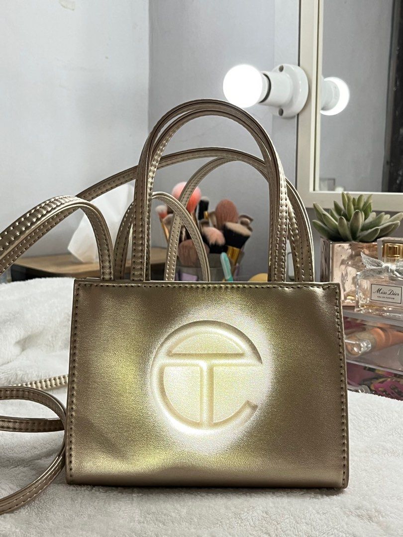 TELFAR Small Shopping Bag in Gold (Category: Luxury Bags & Wallets) located in Cainta. Submitted by sydkyn (Listing ID 1327418910, Image 1). Description: • brand: TELFAR • dimensions: Height - 4 3/4”, Width - 6 5/8”, Depth - 3”, Strap Drop - 21”, Handle Drop -4 3/4” • condition: 10/10 • note: NEVER BEEN USED. bought from the US. packaged in a drawstring bag with screen-printed logo. currently sold out in the official TELFAR website 😳 the iconic 