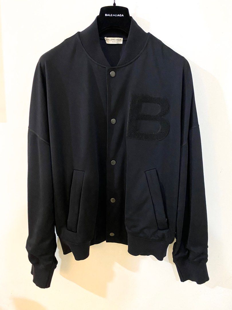 Balenciaga Bomber Jacket (Category: Coats, Jackets and Outerwear) located in Pasig City. Submitted by halffullbutneverfull (Listing ID 1347368104, Image 1). Description: Balenciaga bomber jacket Color: black Soft polyester outer material Soft elastan lining material Embossed logo patch detail Snap metal button Zippered pocket detail Oversized fit Width: 25" Length: 26".