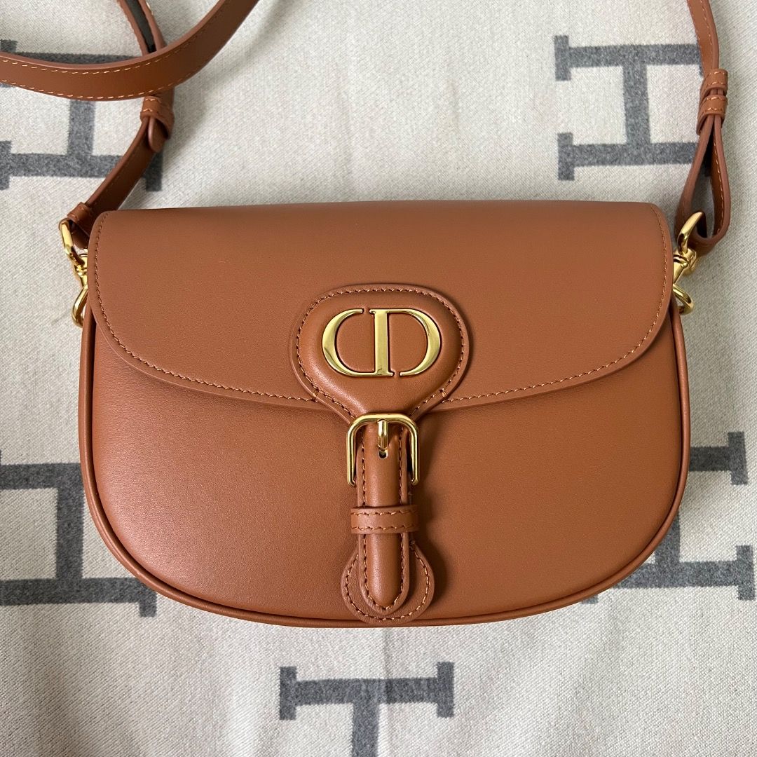 Dior Bobby Medium Bag Cognac-Colored Box Calfskin (Category: Luxury Bags & Wallets) located in Antipolo. Submitted by chanchimj (Listing ID 1338780309, Image 1). Description: The medium silhouette is crafted from cognac-colored box calfskin with a supple suede calfskin interior, and is enhanced by antique gold-finish metal hardware. Its removable and adjustable shoulder strap has a military-inspired buckle and allows it to be carried by hand, wor