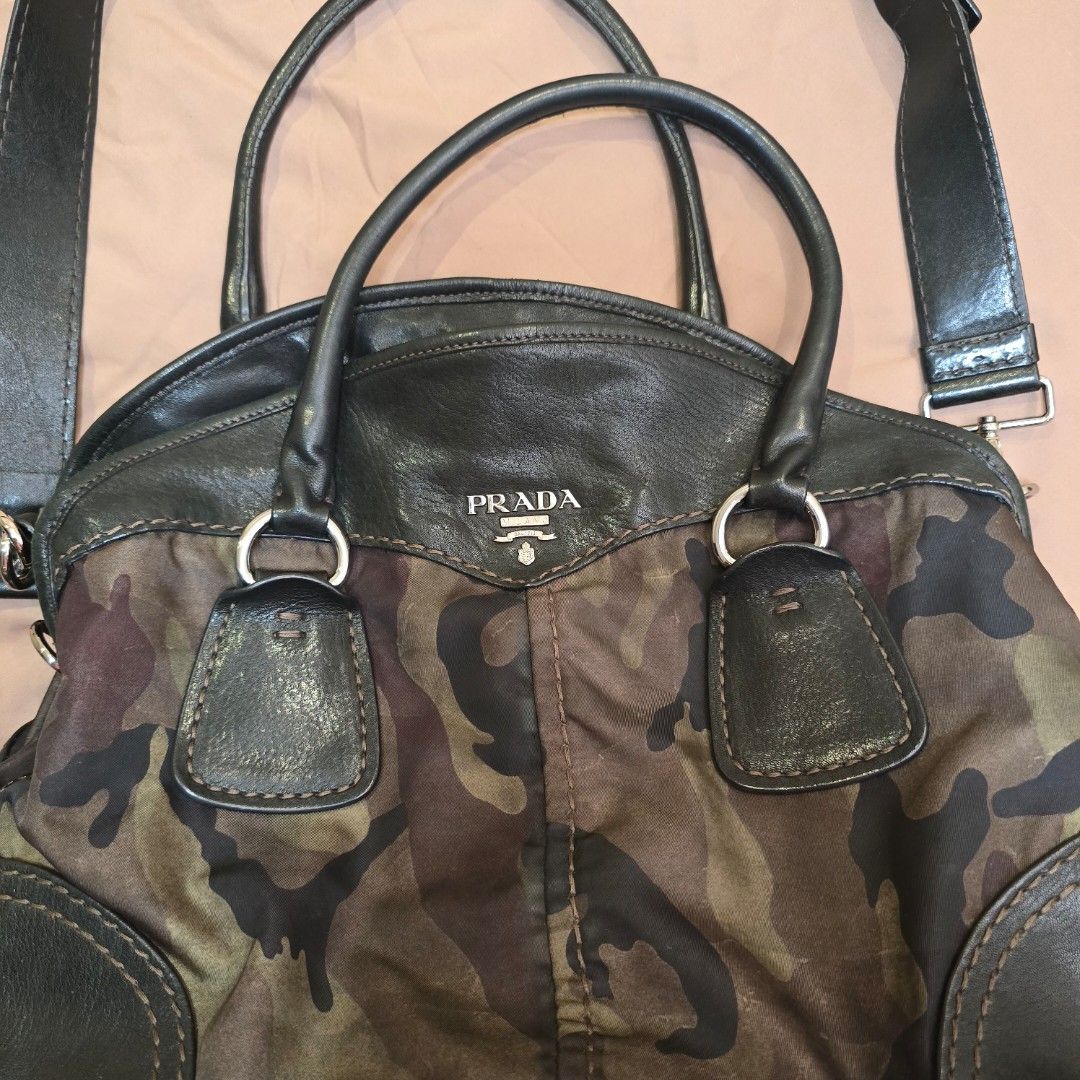 Prada Camouflage Tessuto Bowler Bag from Fall 2010 (Category: Luxury Bags & Wallets) located in Makati City. Submitted by HappyDeclutterer (Listing ID 1349844478, Image 2). Description: One of my favorite bags because of the unique colorway and in my favorite Camouflage print Prada Camouflage Tessuto Bowler Bag from the Fall 2010 collection Black calfskin nappa leather and green and brown camouflage printed nylon with silvertone metal studs linin