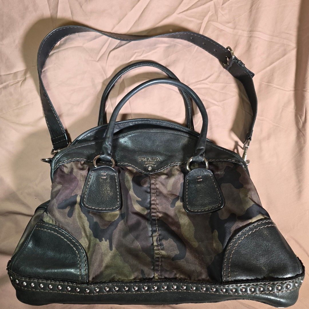 Prada Camouflage Tessuto Bowler Bag from Fall 2010 (Category: Luxury Bags & Wallets) located in Makati City. Submitted by HappyDeclutterer (Listing ID 1349844478, Image 1). Description: One of my favorite bags because of the unique colorway and in my favorite Camouflage print Prada Camouflage Tessuto Bowler Bag from the Fall 2010 collection Black calfskin nappa leather and green and brown camouflage printed nylon with silvertone metal studs linin