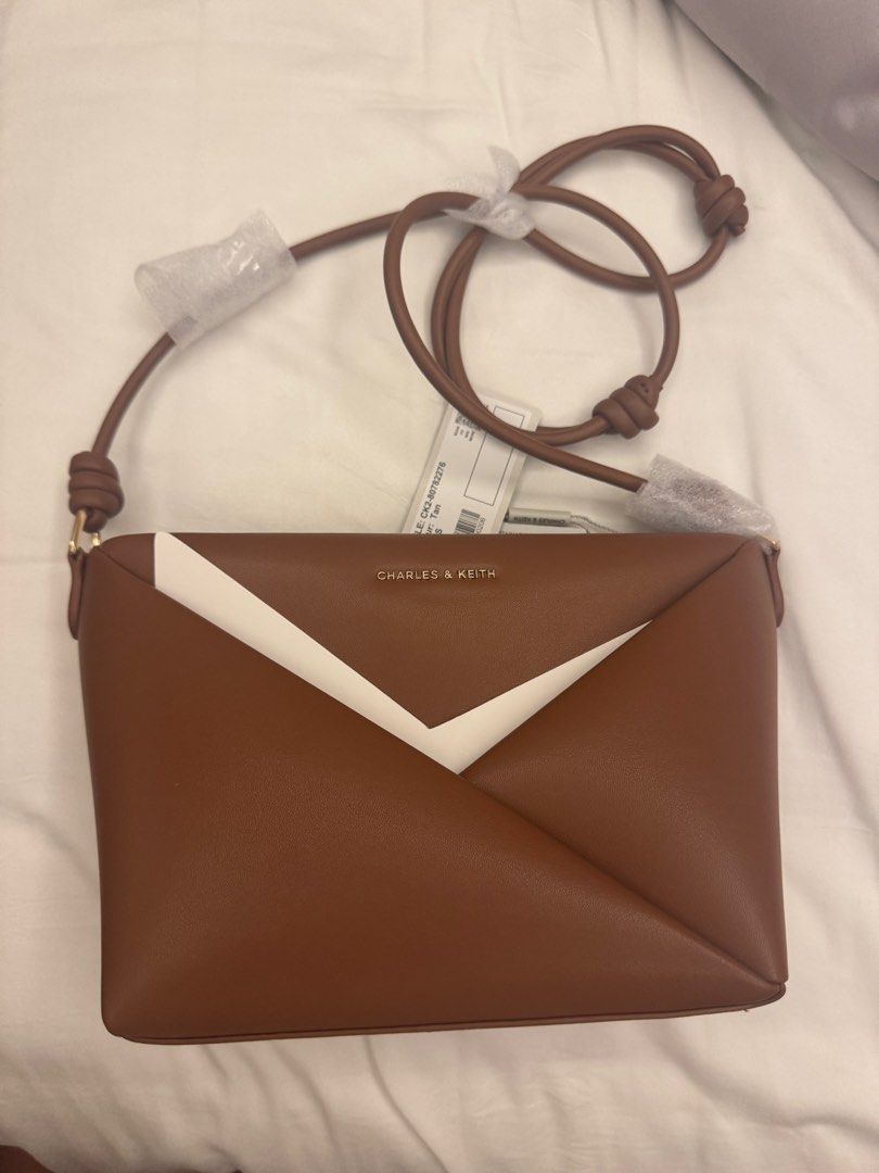 Charles & Keith Tan Crossbody Bag (Category: Cross-body Bags) located in Makati City. Submitted by masaca (Listing ID 1397536995, Image 2). Description: - Charles & Keith crossbody bag - Color: Tan - Unique envelope design with white accent - Features a zip closure - Includes a long strap - Size: S - Brand new with original tags.