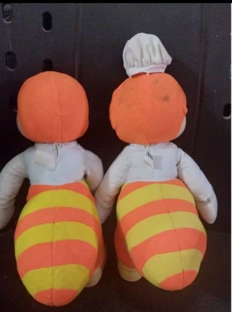 Jollibee Plush Toy Set (Category: Plushies & Soft Toys) located in Abucay. Submitted by g_treasures (Listing ID 1397426433, Image 3). Description: - Set includes two Jollibee plush toys. - One Jollibee is wearing a chef's hat. - Both have orange pants with yellow stripes. - Both have white shirts and black bow ties. - Features tan skin and shoes..