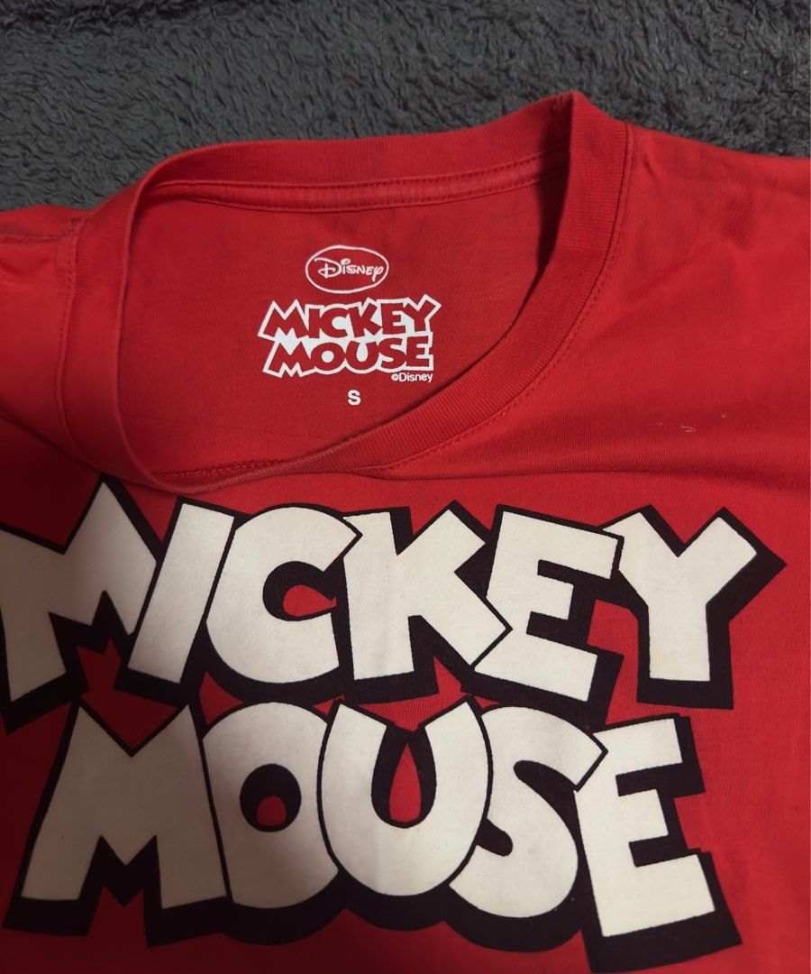 Original Disney Mickey Mouse Red T-shirt (Category: Babies & Kids Fashion) located in Manila. Submitted by AAA09876 (Listing ID 1397619241, Image 2). Description: - Red Mickey Mouse t-shirt - Size: Small-Medium fit - Features a large "Mickey Mouse" graphic on the front - Mickey Mouse character pattern at the bottom - Crew neck - Short sleeves.