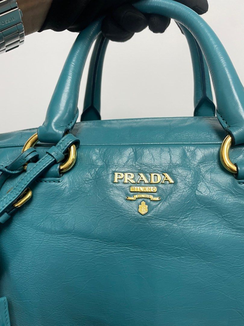 Prada Leather Handbag with Shoulder Strap (Category: Luxury Bags & Wallets) located in Quezon City. Submitted by shoppersluxe2394 (Listing ID 1397673129, Image 2). Description: - Authentic Prada handbag - Stunning teal color - Gold-tone hardware - Detachable shoulder strap - Includes key and luggage tag - Double top handles - Secure zip closure - Iconic Prada logo - Textured leather finish.