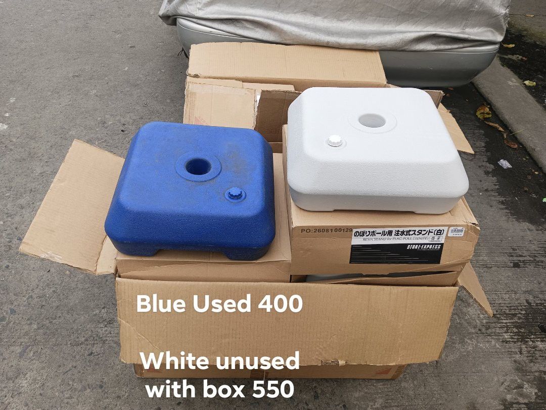 Umbrella Base - Blue and White (Category: Umbrellas) located in Quezon City. Submitted by huntbook.ph (Listing ID 1397686164, Image 1). Description: Available umbrella bases in blue (used) and white (unused with box). The blue base used is priced at 400 PHP, while the white base is available for 550 PHP. Both are square-shaped. The white base comes with its original box..